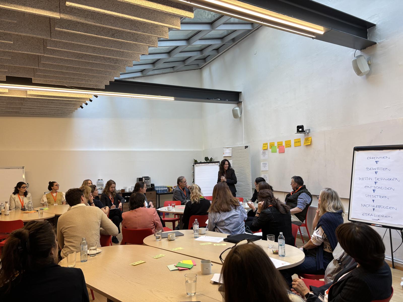 Blick in den Workshop-Raum mit Teilnehmenden an Tischen und Flipchart zum Due-Diligence-Prozess